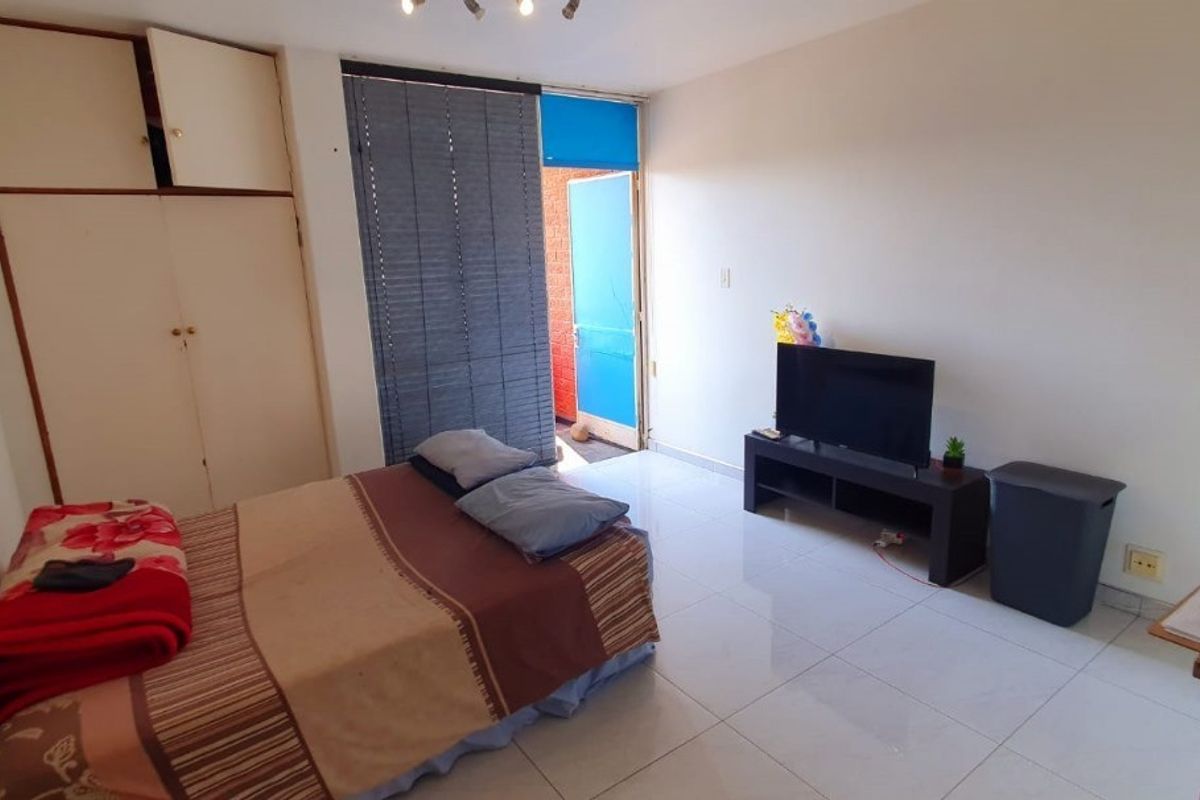 A bedroom featuring tiled flooring, a built-in wardrobe with a damaged door, and direct access to an outdoor area.