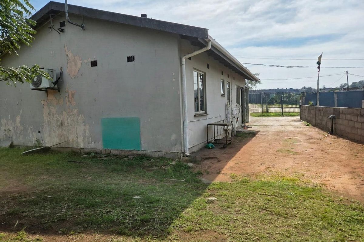 Rear view of the property showing exterior wall with peeling paint, guttering, and an outdoor air conditioning unit.