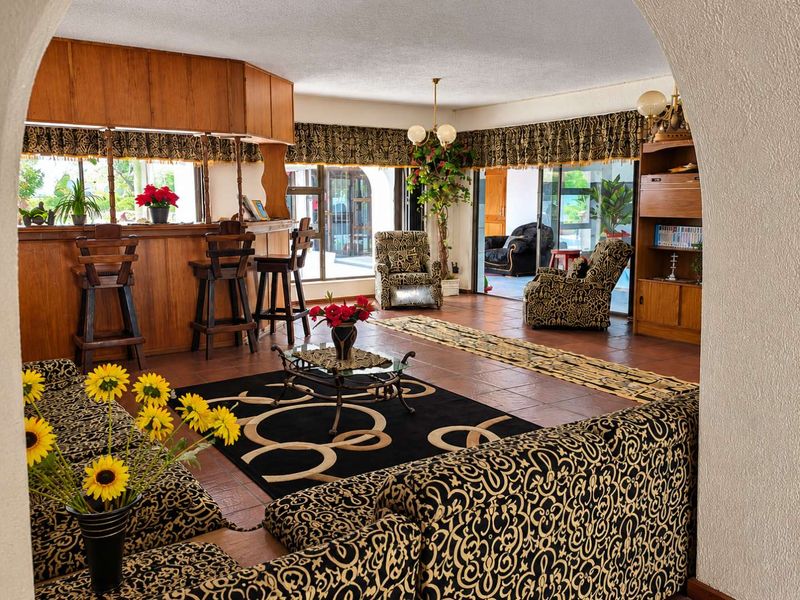 Spacious living area featuring a built-in wooden bar, terracotta flooring, and large sliding glass doors providing access to the outdoor area.
