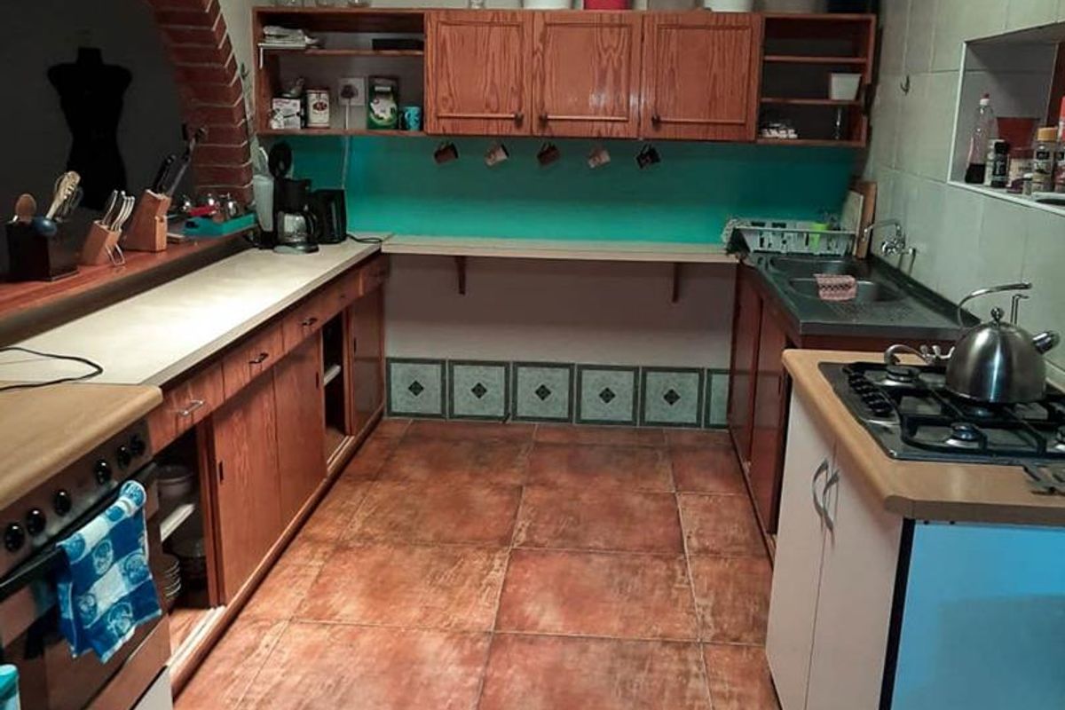 A functional kitchen featuring wooden cabinetry, a built-in gas hob, double sink, and a distinctive brick archway detail.