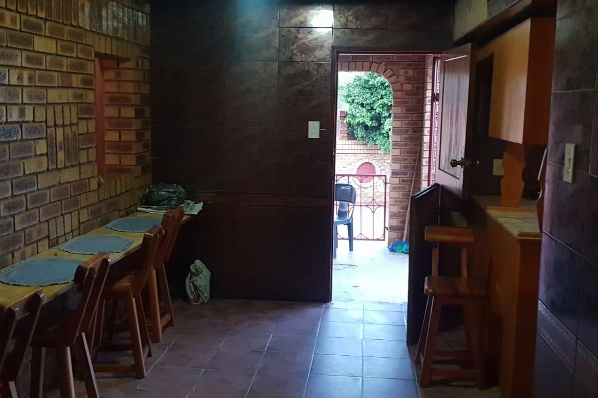 A rustic interior space featuring exposed brick walls, tiled flooring, and a doorway leading to an outdoor area.