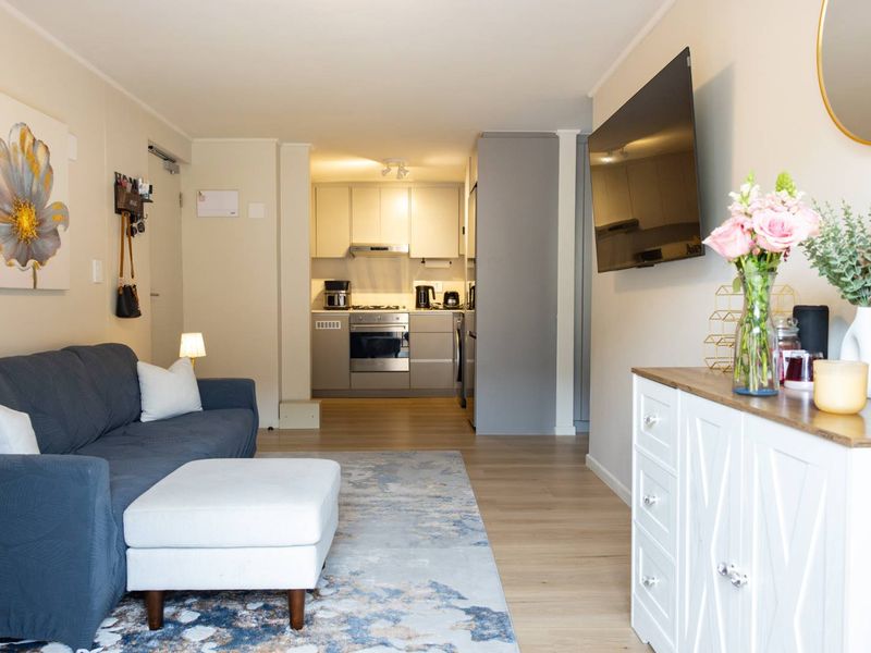 A well-maintained open-plan living area featuring a modern kitchen with built-in cabinetry, integrated oven, and gas hob, seamlessly connected to the lounge space.