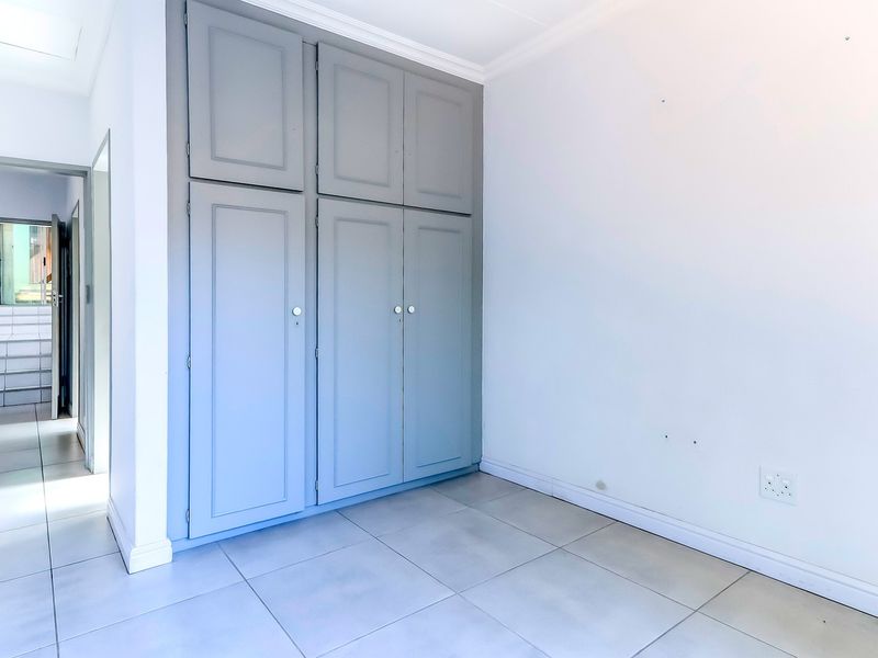 A bright, empty bedroom featuring neutral tiled flooring and ample built-in cupboard storage, offering a clean canvas for personalization.