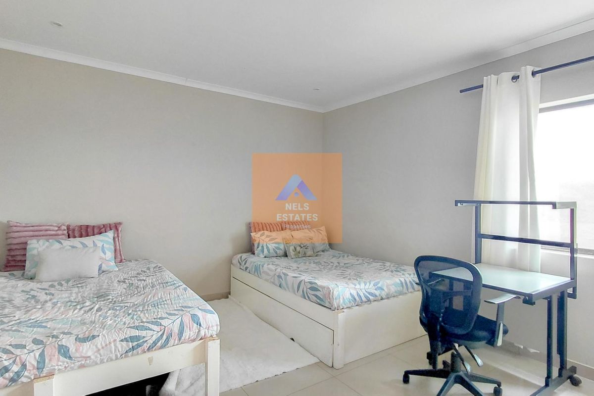 A well-lit bedroom featuring neutral wall tones, tiled flooring, and cove cornicing, providing a clean and functional living space.