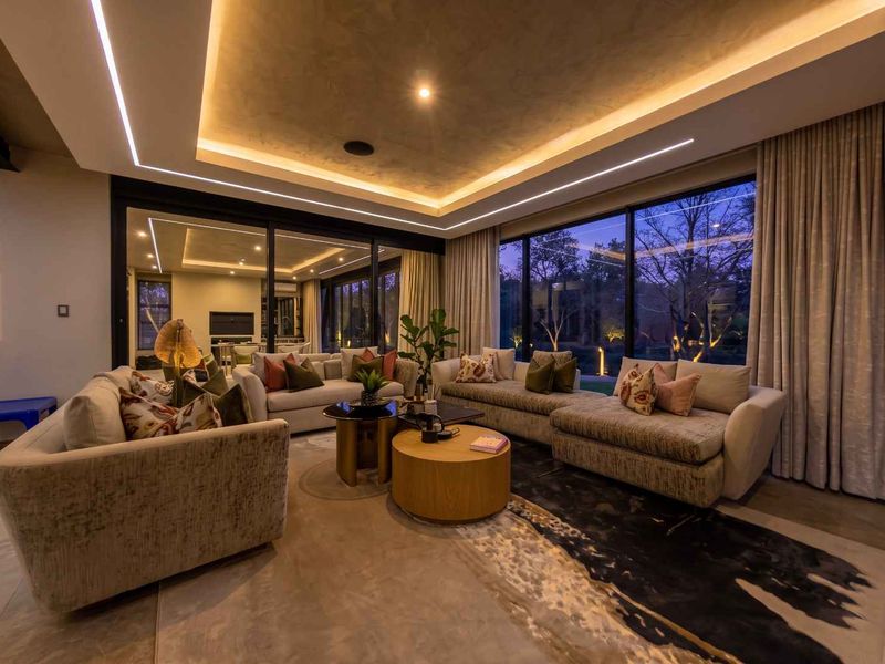 Modern living room featuring a sophisticated recessed tray ceiling with integrated LED lighting, polished concrete floors, and expansive sliding glass doors opening to the garden.
