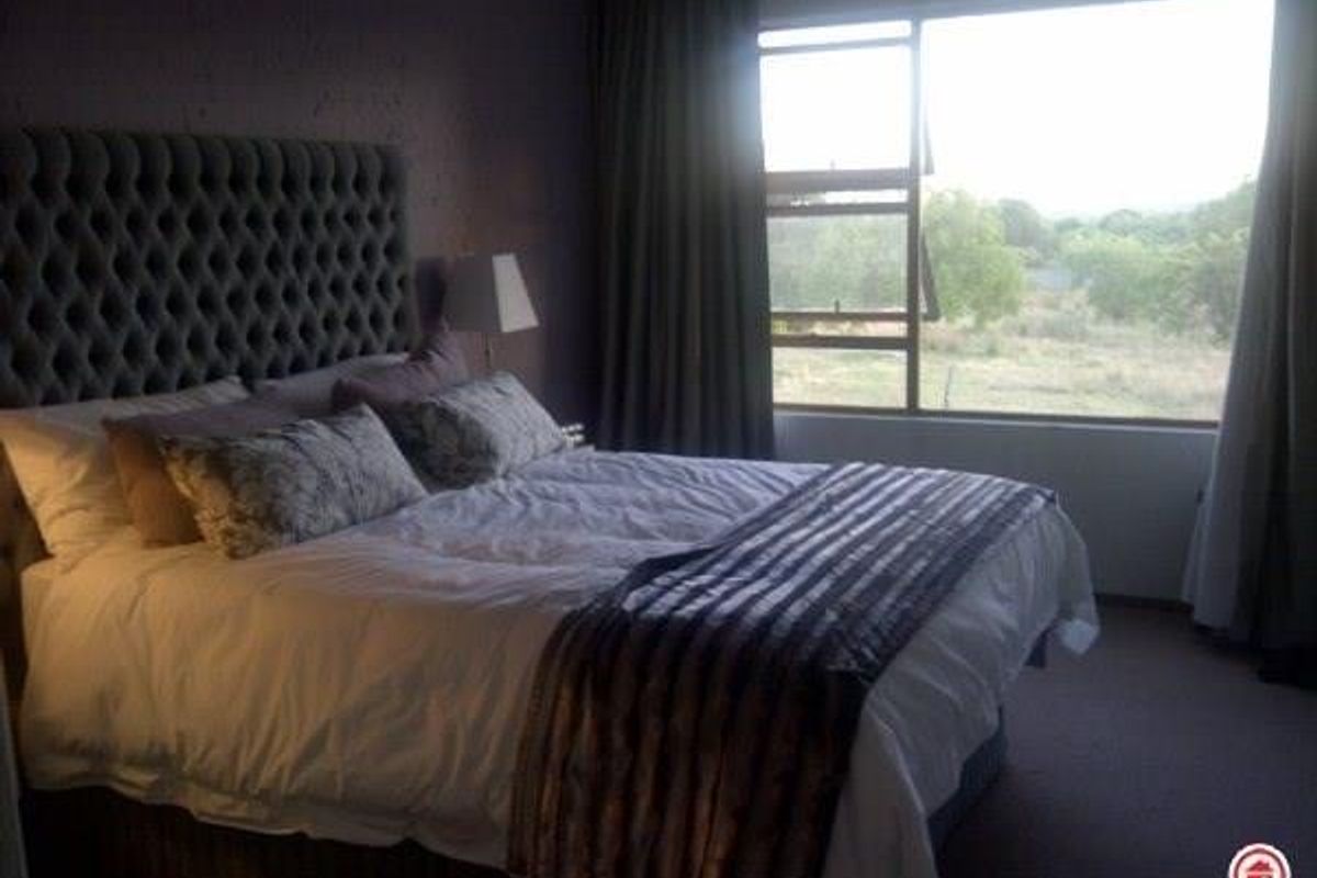 A bedroom featuring carpeted flooring and a large window with natural light, offering a view of the surrounding landscape.