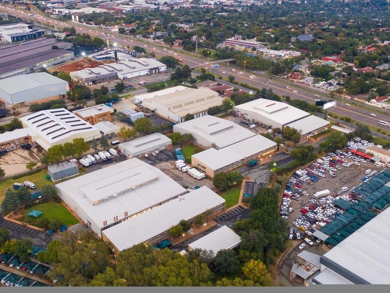 Aerial view of a large industrial park featuring multiple warehouse buildings, extensive paved parking areas with shade structures, and convenient highway access.