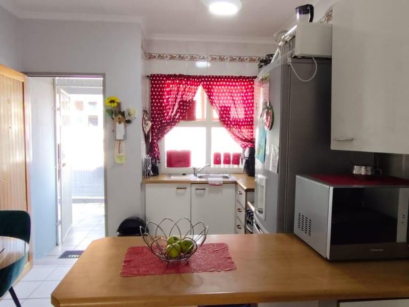 A functional kitchen featuring built-in cabinetry, a countertop, and tiled flooring, with an adjacent dining area and direct access to an exterior space.