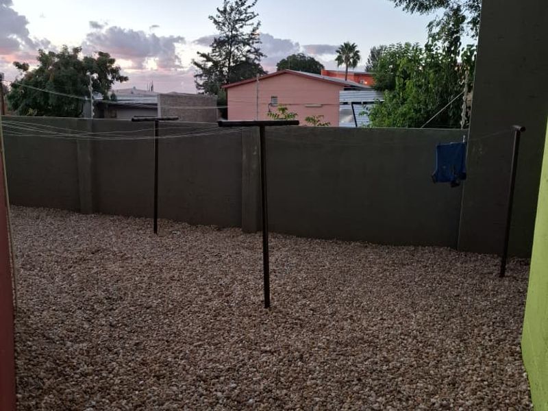 A private rear courtyard area featuring gravel ground cover, perimeter walling, and electric fencing, suitable for outdoor utility use.