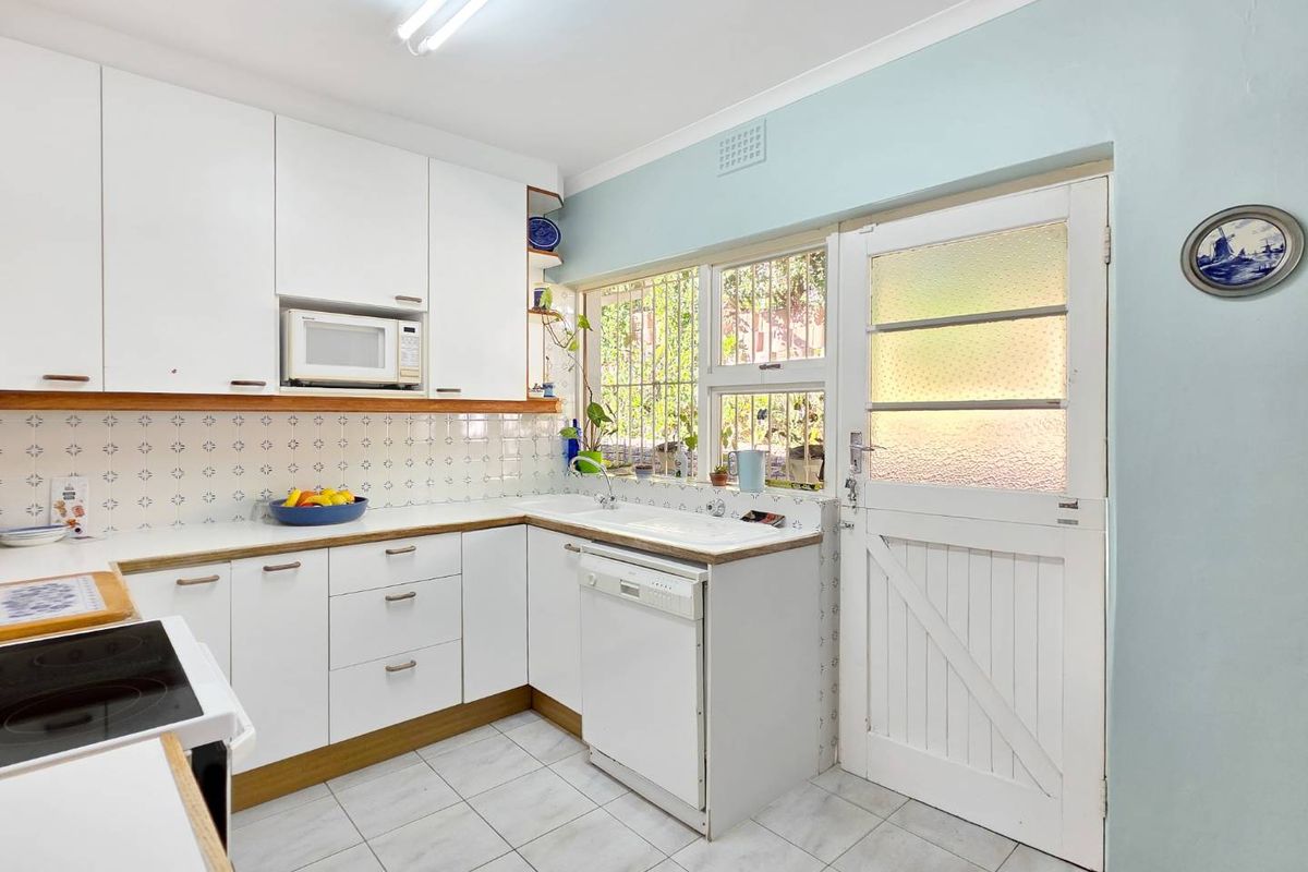 Functional kitchen featuring white cabinetry, tiled backsplash, integrated appliances, and a stable door leading to the exterior.