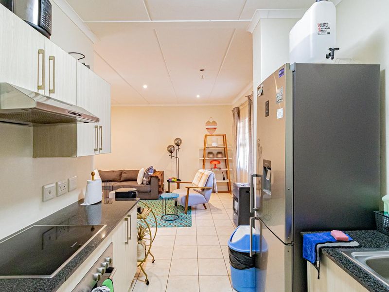 Open-plan kitchen and living area featuring modern cabinetry, granite countertops, integrated hob, and tiled flooring throughout the space.