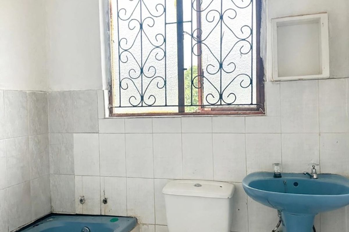 A dated bathroom featuring a blue bathtub and pedestal basin, requiring renovation to update the finishes and address visible tile and maintenance issues.