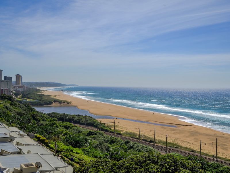A panoramic coastal view overlooking the beach, coastline, and surrounding landscape from an elevated vantage point.