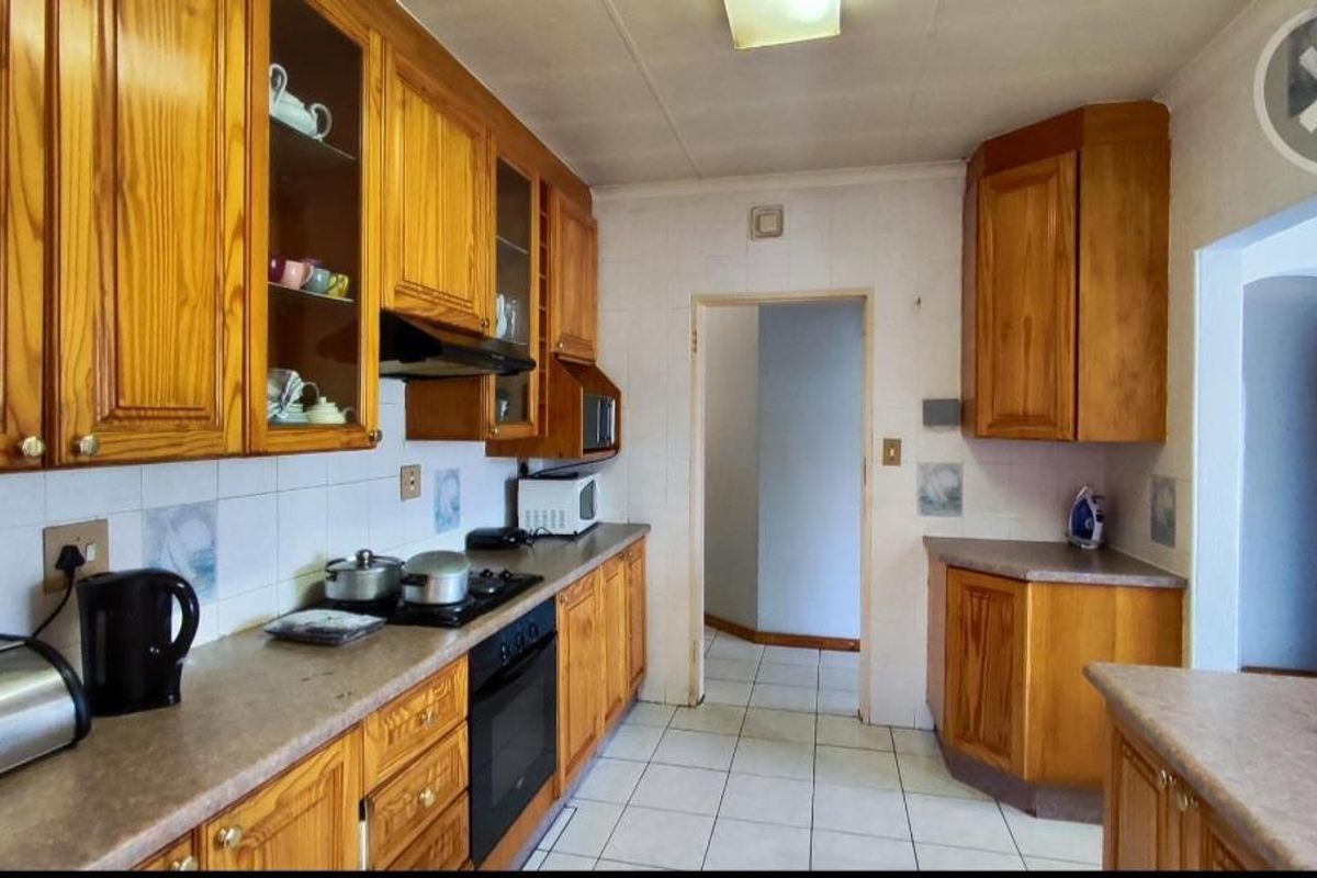 A functional kitchen featuring traditional timber cabinetry, tiled flooring, built-in oven and hob, and ample counter space for meal preparation.