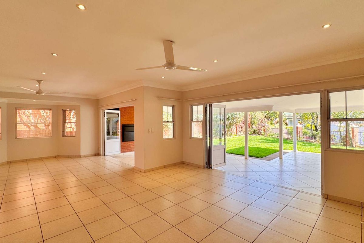Spacious, light-filled living area featuring tiled floors, recessed lighting, and seamless flow through bi-fold doors to a covered patio and garden.