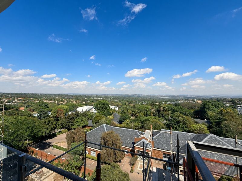 Elevated panoramic view overlooking the surrounding neighborhood and lush greenery, captured from a balcony with a glass balustrade.