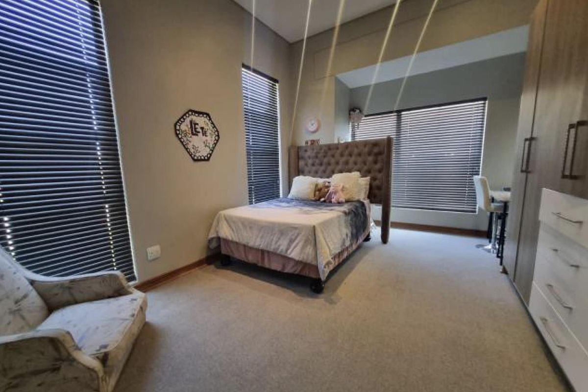 Spacious bedroom featuring neutral carpeting, built-in cabinetry, and large windows fitted with dark horizontal blinds for adjustable natural light.