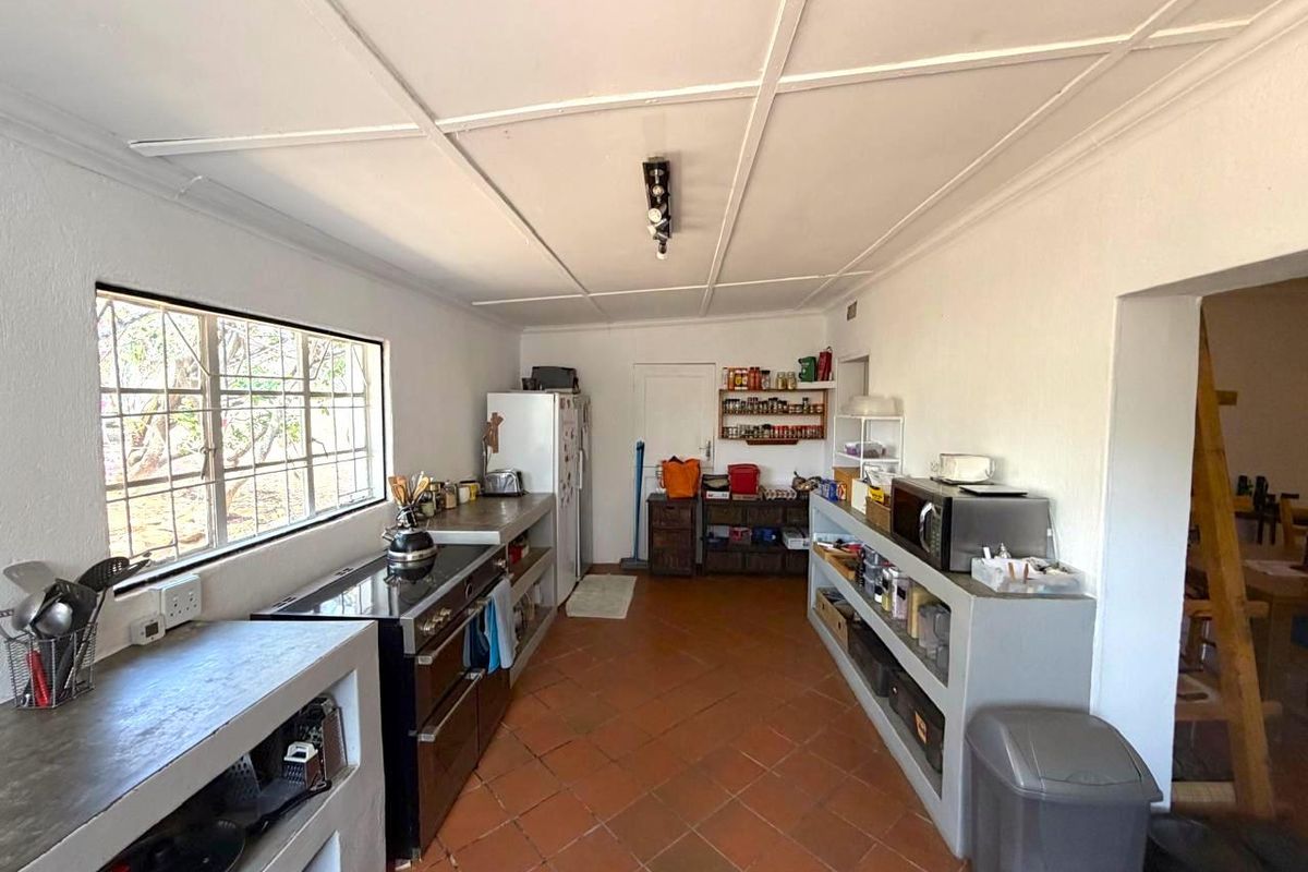 Functional kitchen featuring built-in concrete countertops, tiled flooring, and a freestanding stove, offering a practical layout with potential for modernization.
