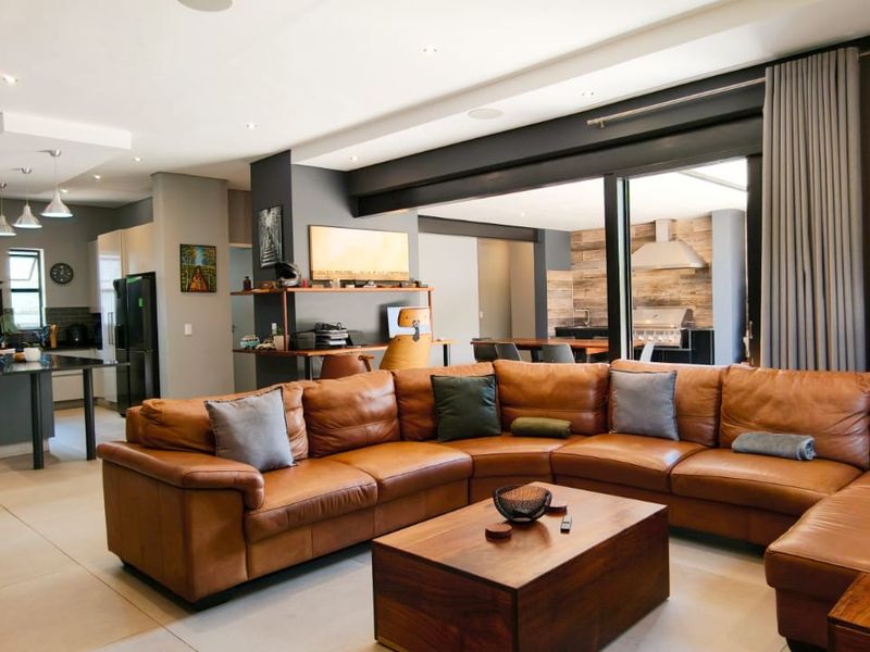 Spacious open-plan living area featuring modern kitchen with island, tiled floors, and seamless flow to an outdoor entertainment space with built-in barbecue.