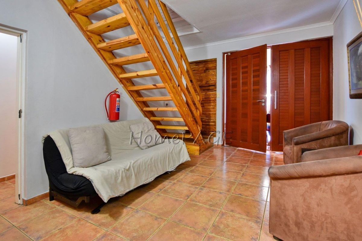 A living area featuring a wooden staircase, tiled flooring, and double wooden entrance doors.