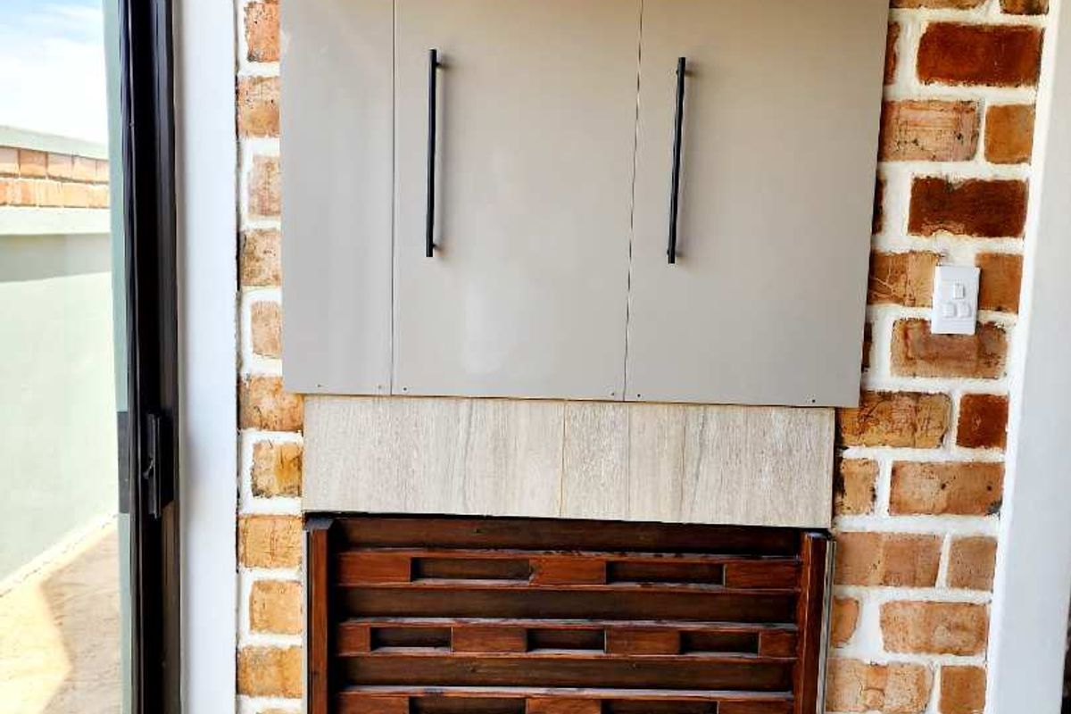 A built-in storage unit featuring modern cabinetry and a decorative timber slatted base, set against a rustic exposed brick feature wall.