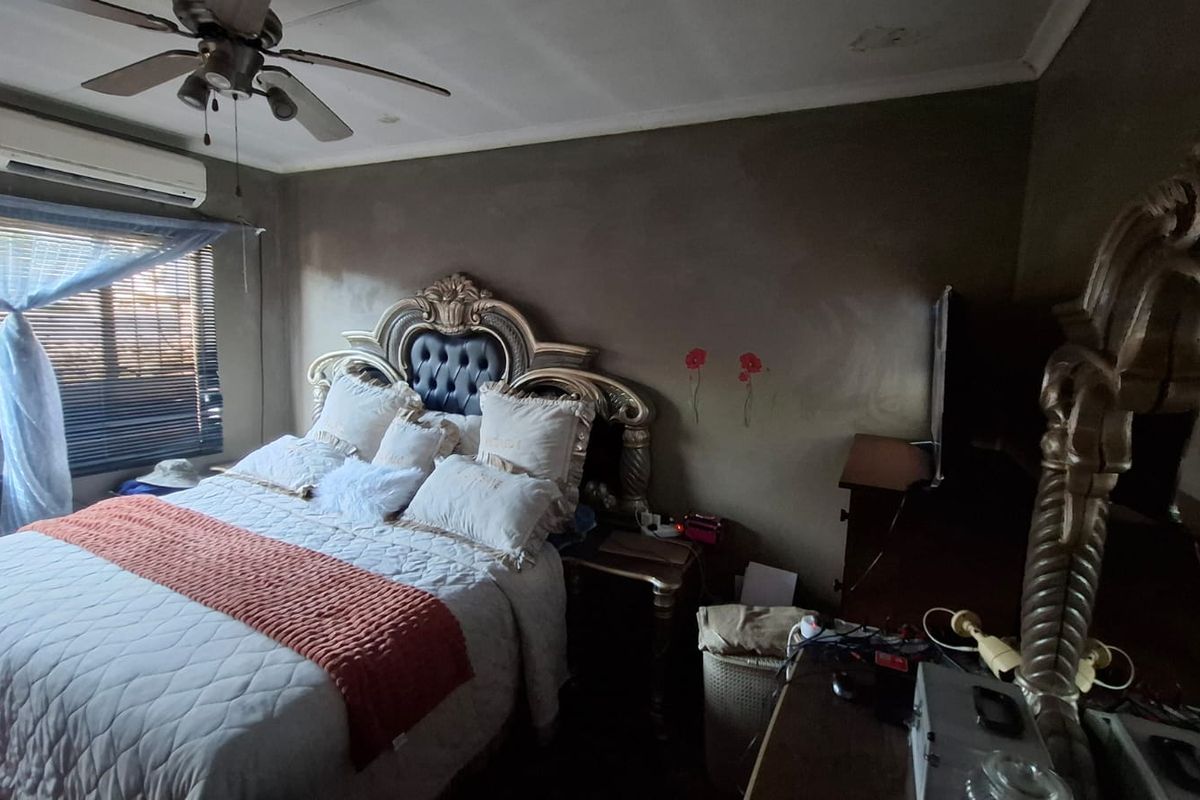 A bedroom featuring a ceiling fan, split-system air conditioning unit, and venetian blinds, requiring cosmetic updates to the wall finishes and ceiling.