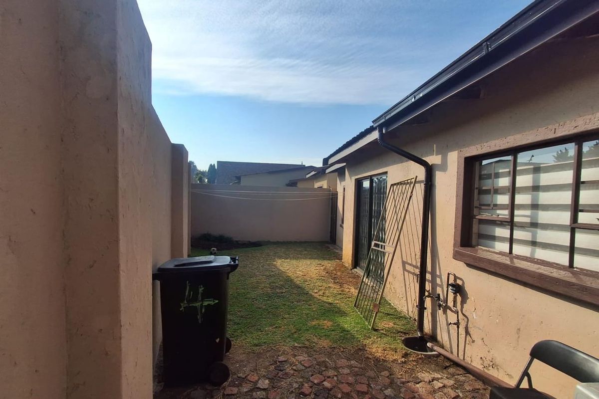 A private rear courtyard area featuring a small lawn, paved section, and perimeter boundary walls, accessible via sliding glass doors.