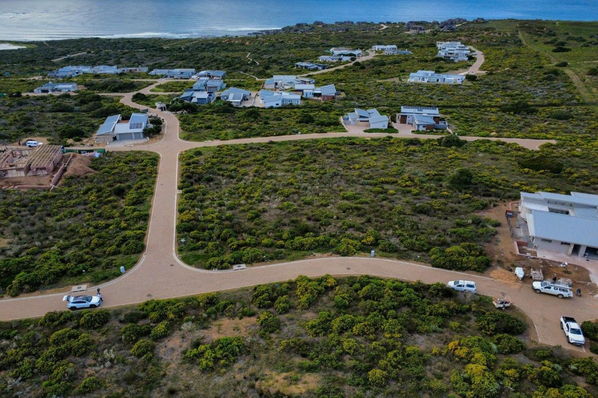 An aerial view of a residential estate featuring paved roads and surrounding coastal vegetation with ocean views in the distance.