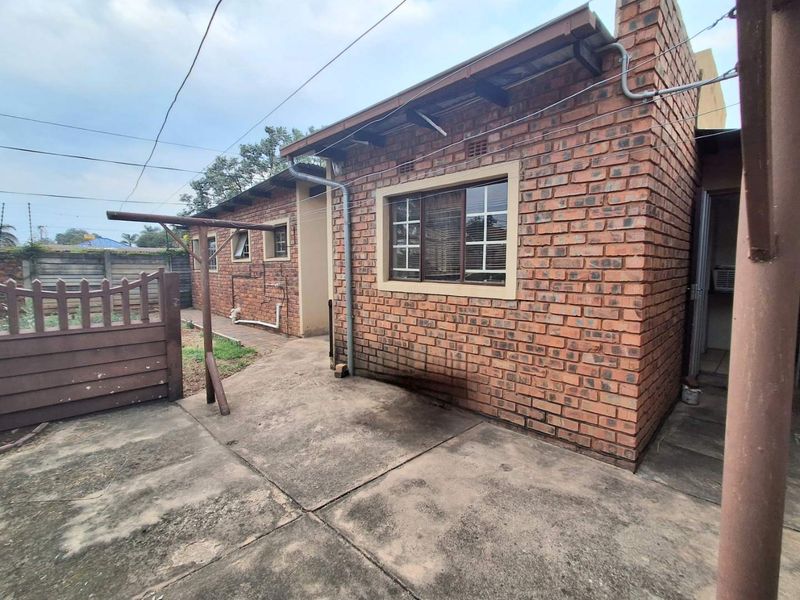 Rear exterior view of the property featuring exposed brick walls, a concrete patio area, and a fixed washing line.