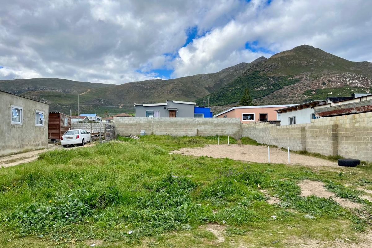 A vacant residential plot featuring concrete block boundary walls and mountain views, offering a blank canvas for future development.