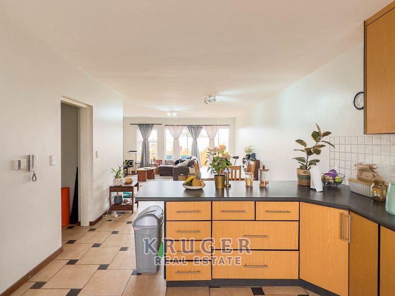 Open-plan kitchen and living area featuring laminate cabinetry, dark countertops, and tiled flooring, creating a functional and connected living space.