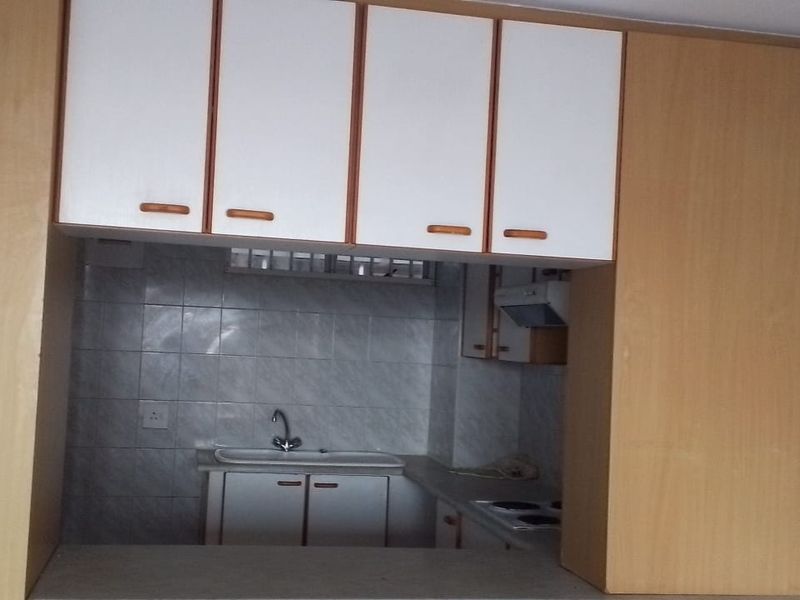 A compact kitchen featuring built-in cabinetry, a tiled backsplash, and a breakfast counter, offering a functional layout ready for modern updates.