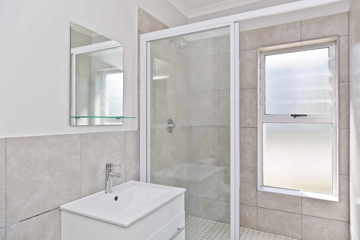 A modern bathroom featuring a glass-enclosed shower, a contemporary vanity with a basin, and neutral wall tiling.