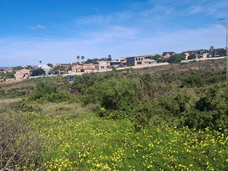 A wide-angle view of the vacant residential land, showcasing the surrounding coastal neighborhood and natural landscape.