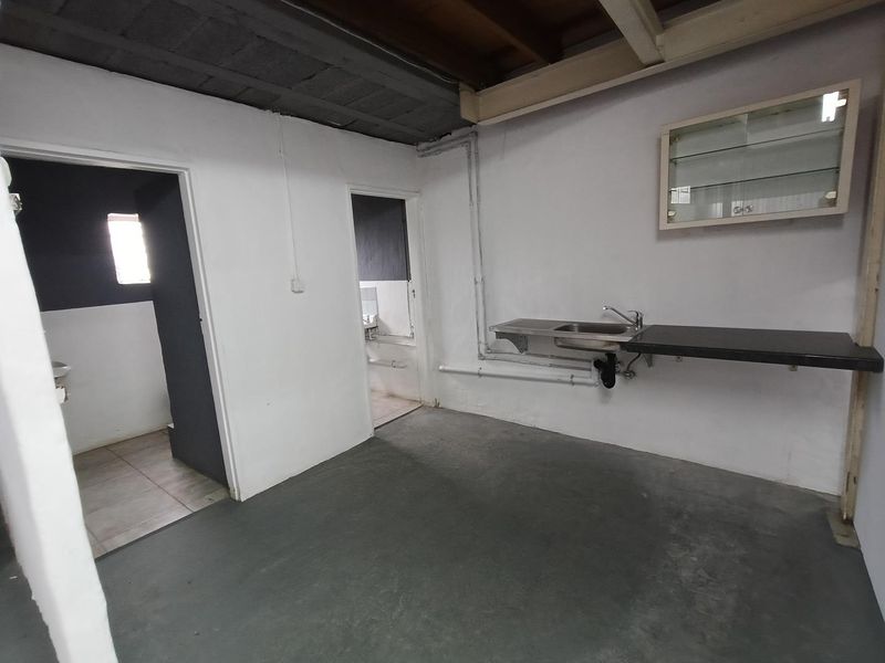 A functional utility space featuring a stainless steel sink, wall-mounted storage, and exposed industrial-style ceiling, providing a versatile area for various operational needs.