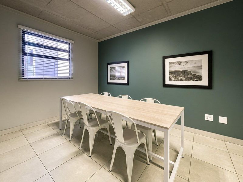 A functional office space featuring tiled flooring, a large window with venetian blinds, and a feature wall.