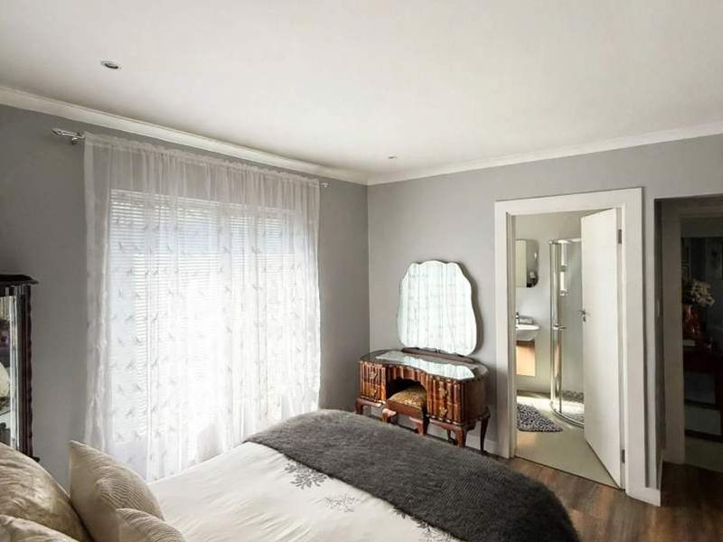 A well-maintained bedroom featuring laminate flooring, recessed lighting, and direct access to an en-suite bathroom.