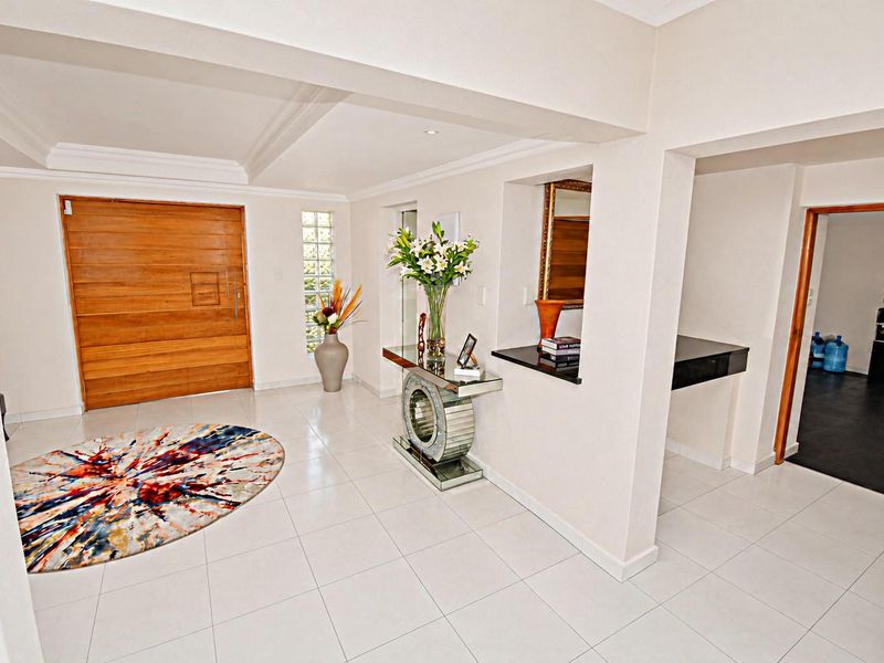 Spacious entrance hall featuring a solid timber front door, decorative glass block window, and neutral tiled flooring with a coved ceiling.