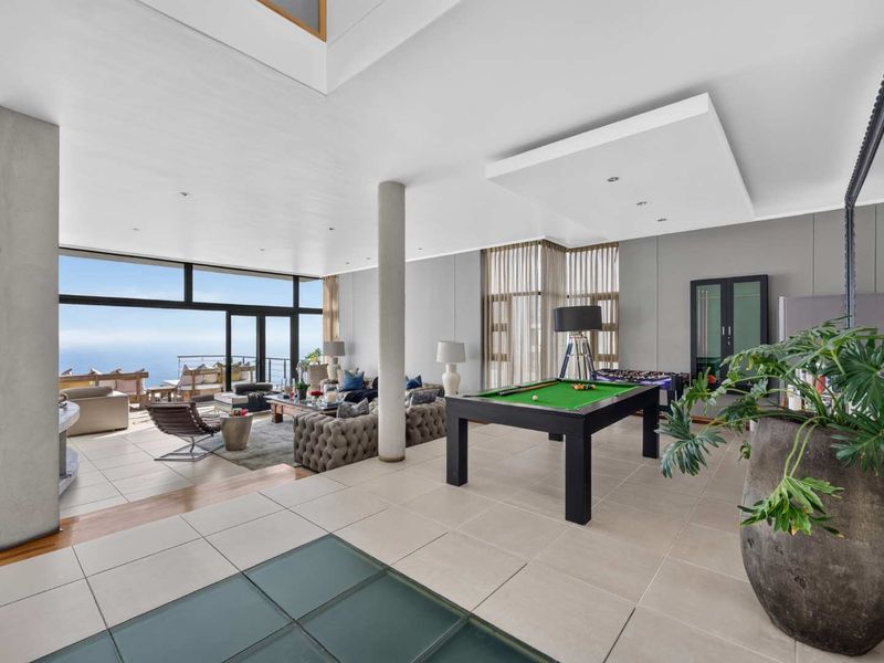 Spacious open-plan living area featuring large format tiles, structural columns, and expansive floor-to-ceiling glass doors offering panoramic ocean views.