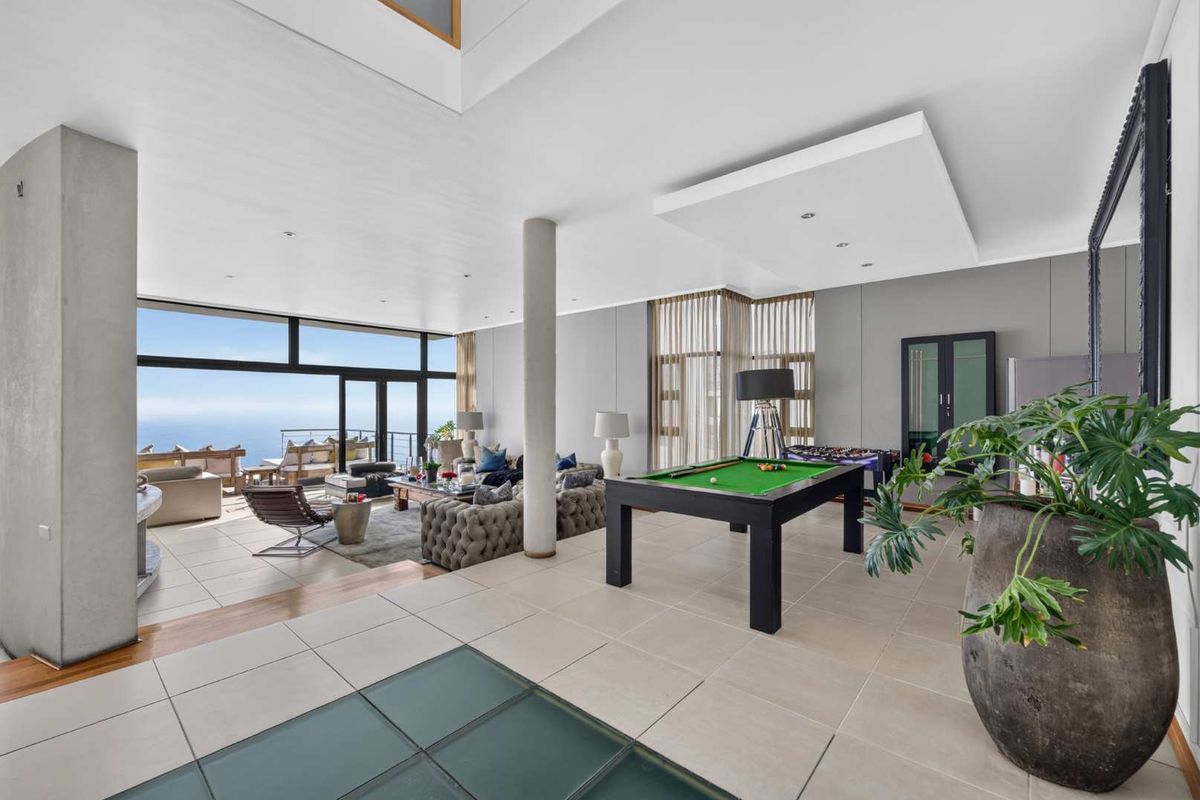Spacious open-plan living area featuring large format tiles, structural columns, and expansive floor-to-ceiling glass doors offering panoramic ocean views.