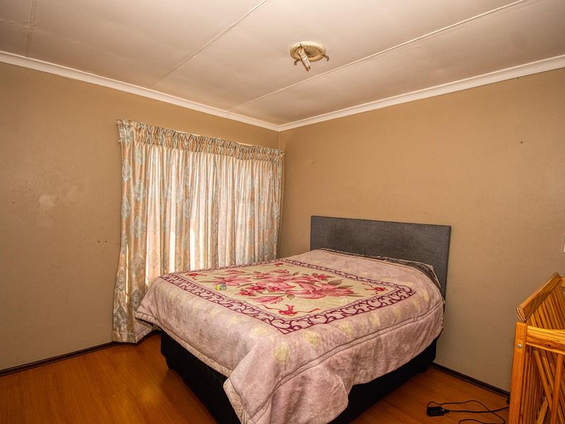 A standard bedroom featuring laminate flooring, built-in wardrobe storage, and neutral wall finishes, offering a functional space ready for cosmetic updates.