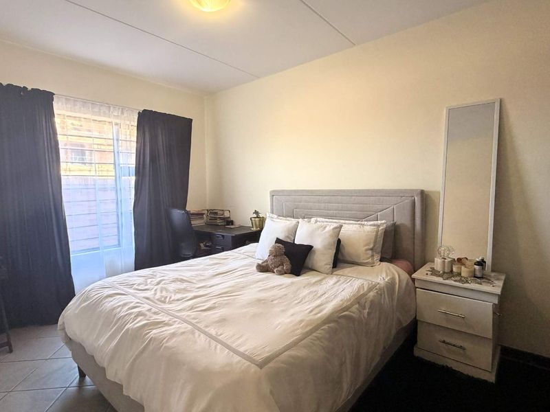 A functional bedroom featuring tiled flooring, a built-in wardrobe, and a window fitted with security bars for added peace of mind.