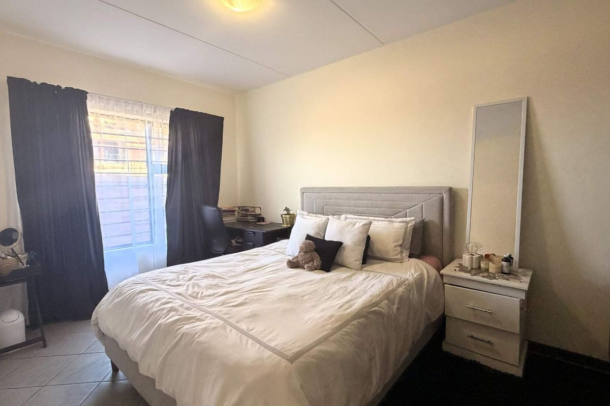 A functional bedroom featuring tiled flooring, a built-in wardrobe, and a window fitted with security bars for added peace of mind.