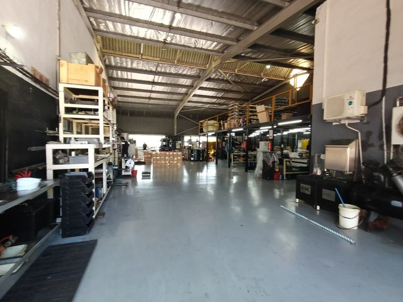 Spacious industrial warehouse featuring high ceilings with exposed steel trusses, a functional mezzanine level, and durable epoxy-coated concrete flooring.