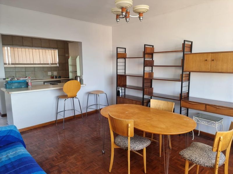 Open plan living and dining area featuring parquet flooring and a convenient kitchen pass-through window with a breakfast bar.