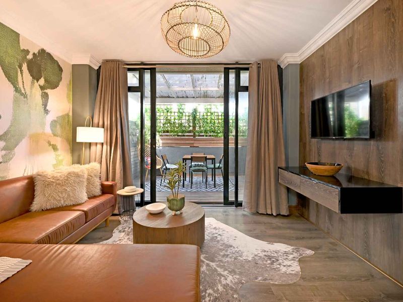 A well-appointed living room featuring wood-look flooring, crown molding, and sliding glass doors that open onto a private balcony.