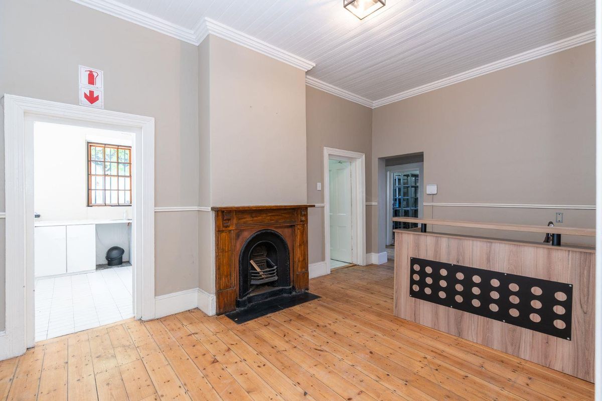 Spacious living area featuring original timber flooring, a classic fireplace with a timber mantelpiece, and decorative crown molding.
