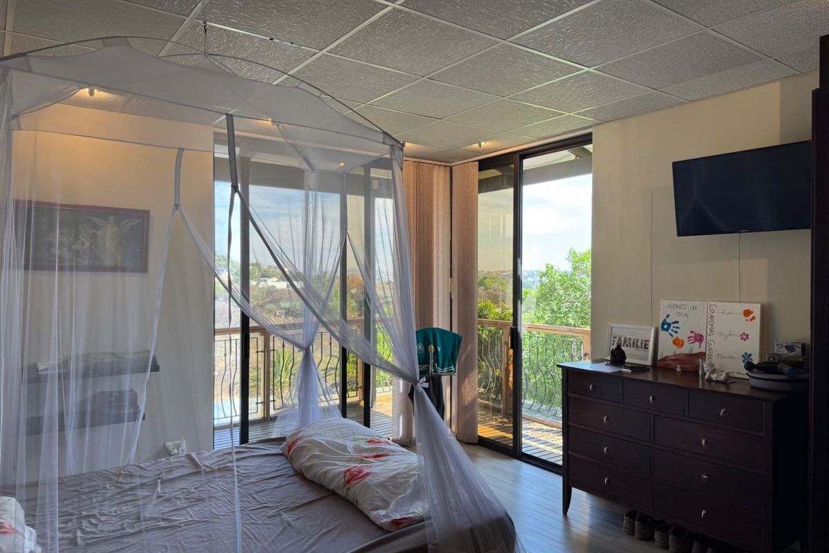 Spacious bedroom featuring large sliding glass doors that open onto a private balcony with scenic views and wood-look flooring.
