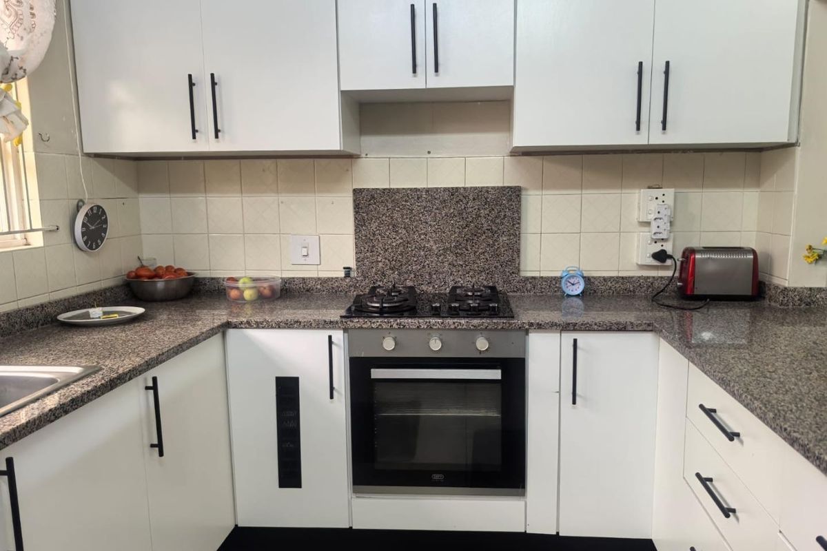 A functional kitchen featuring white cabinetry, granite countertops, a built-in oven, and a gas hob with a tiled backsplash.