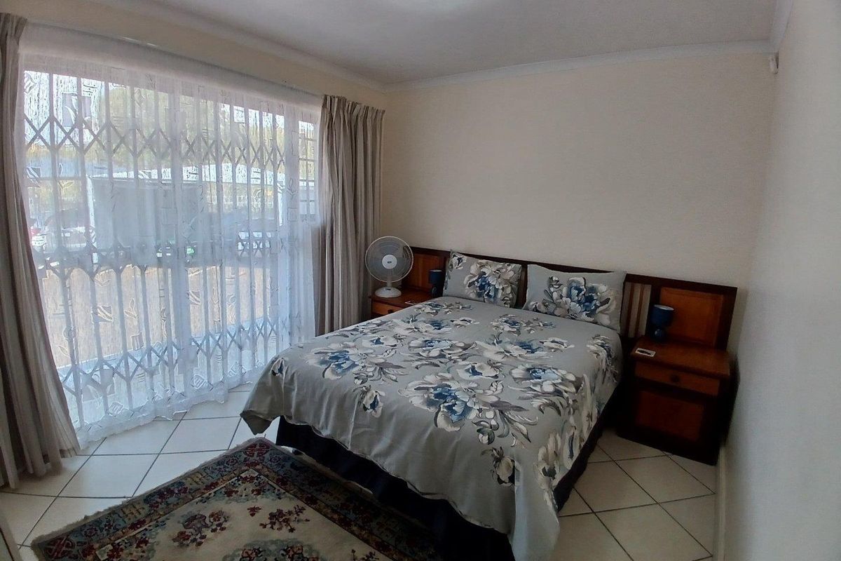 A bedroom featuring tiled flooring, a built-in headboard, and a sliding door with a security gate providing access to the exterior.